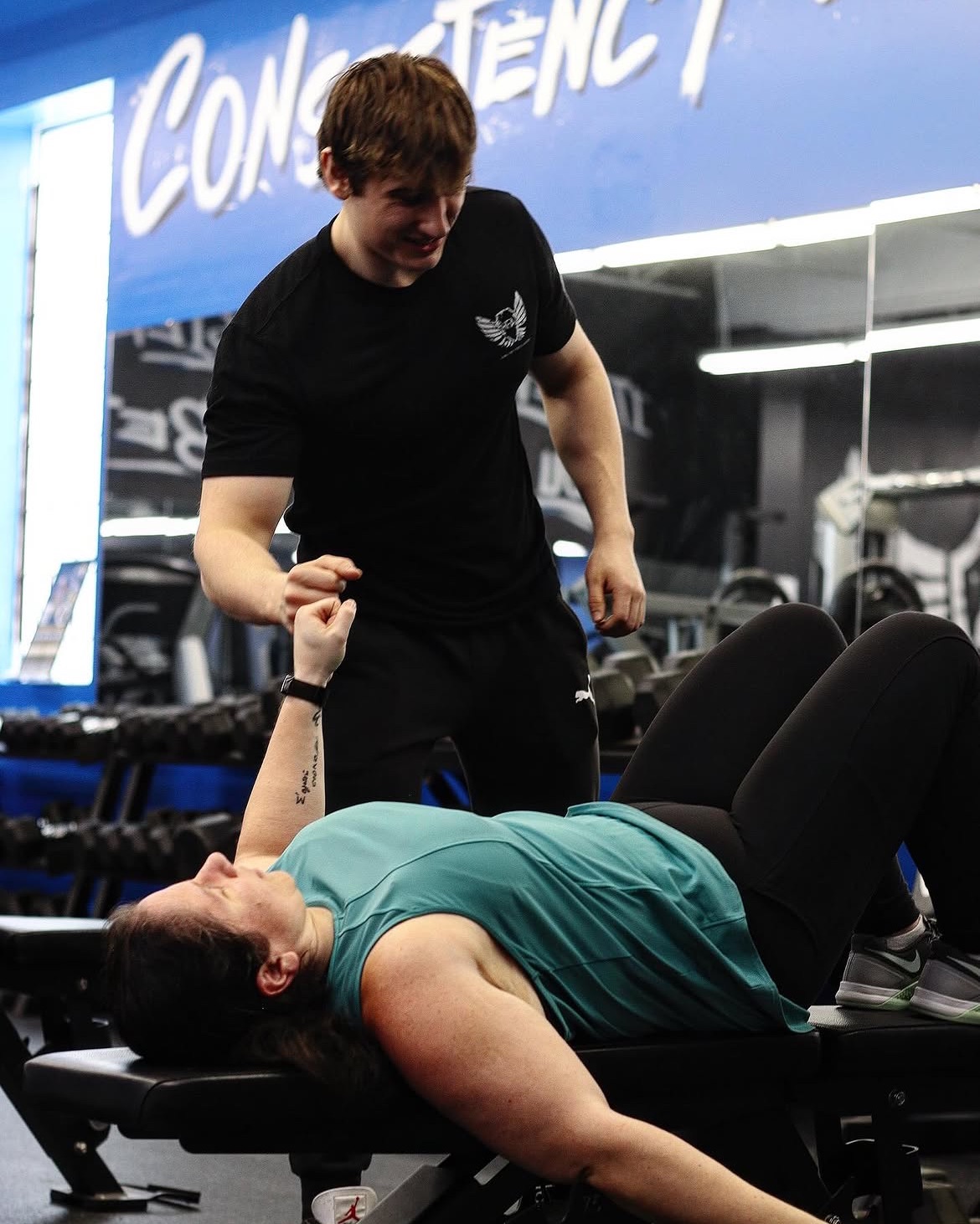 Alex fist-bumping a client between sets on the gym floor